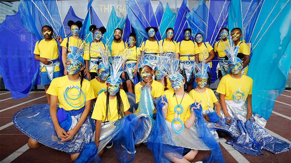 Group of 18 young people dressed in bright colours with face paint