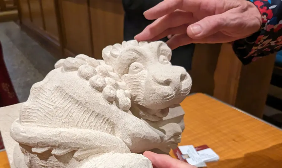 A stone carving of a lion from the Maison Dieu building being touched as part of a tactile tour