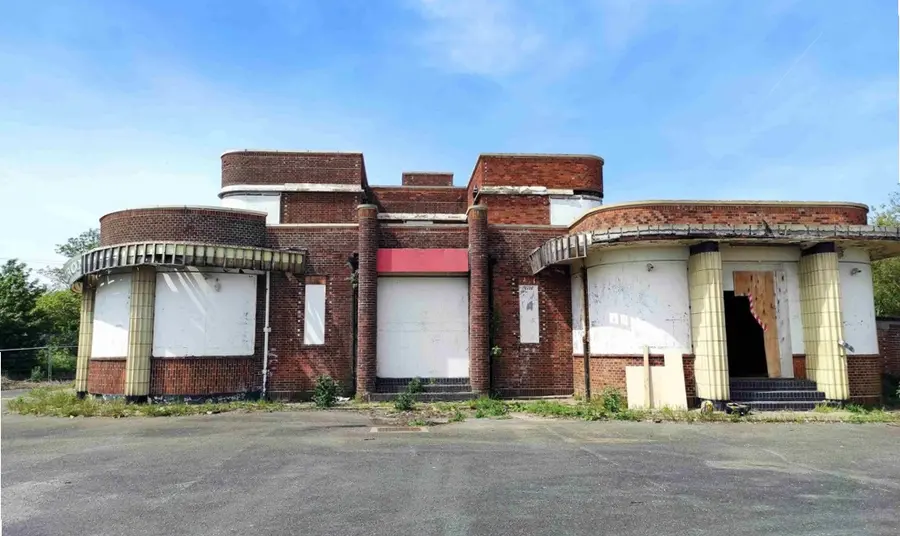The facade of the Iron Duke as it stands today, with the curved arc deco windows boarded up and signs of decay.
