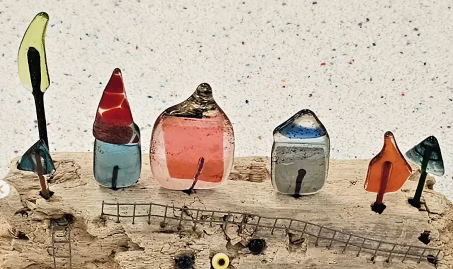 A close up of an artwork by a 10-year old with small houses made from reclaimed glass on driftwood