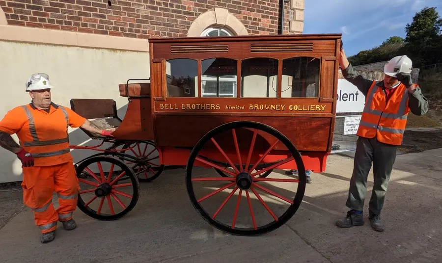 Horse-drawn ambulance at Land of Iron. Credit: Land of Iron Two workmen standing either side of the horse-drawn ambulance