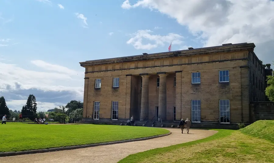 Belsay hall and gardens The facade of Belsay Hall on a sunny day, with visitors exploring the grounds