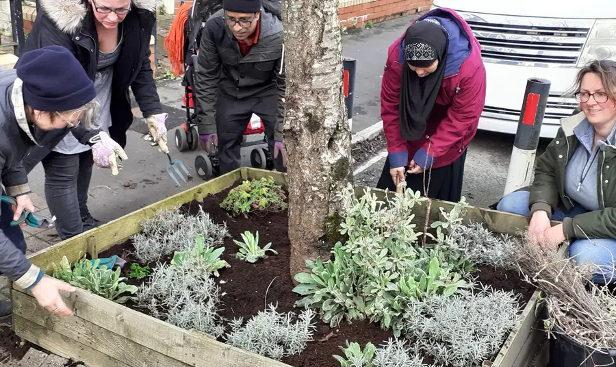 People tend to a large street planter