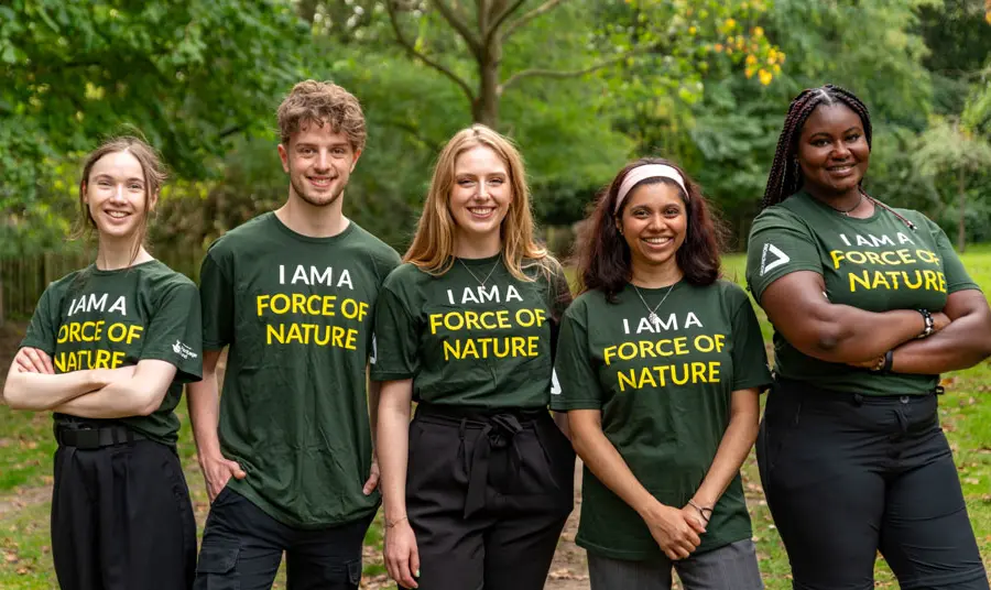 New to Nature trainees Pum person ifanc yn sefyll ochr yn ochr yn gwisgo crysau-t â 'we are a force of nature' arnynt