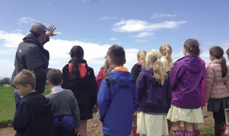 A school visiting the archaeological site Children listening to a talk about the archaeological site