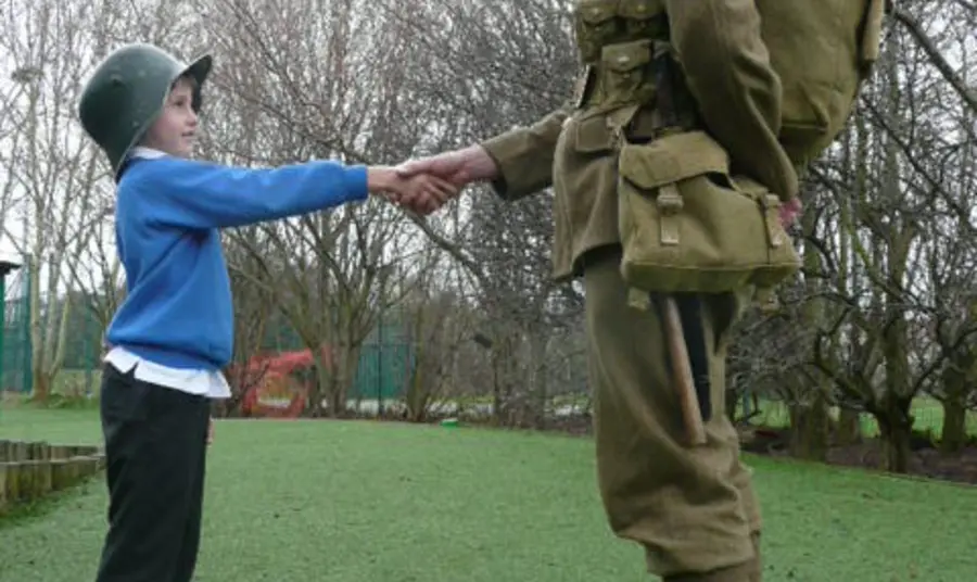 A young participant shaking hands with an actor in period uniform