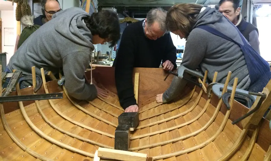 Anchor and Sail: Restoring Maritime Heritage to the Clyde People working on the inner side of the hull of a wooden boat