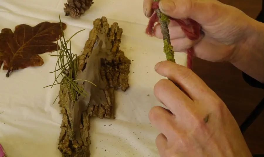 Arts on Prescription - Heritage for Health Participant feeling a piece of bark along with other items from the natural environment