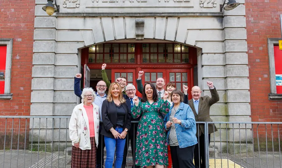 The Tylorstown community celebrate outside the Welfare Hall. A group of different ages from the Tylorstown community celebrate outside the Welfare Hall, smiling and raising their hands in the air.