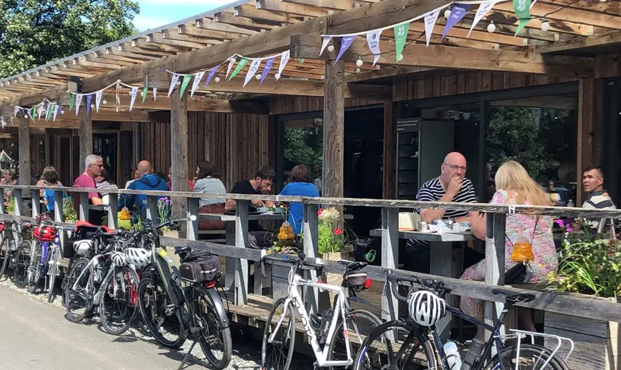 Visitors enjoying food and drinks at a cafe with bikes stacked along the railings