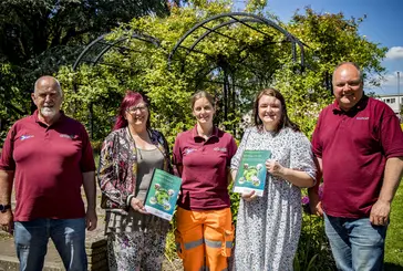 Five people standing in the park on a sunny day