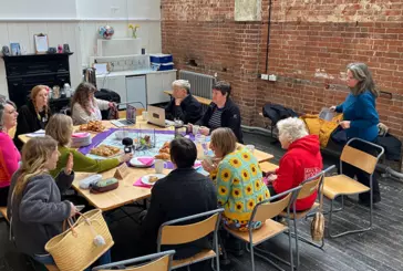 A photograph of a group of women in conversation while sitting around at a large table