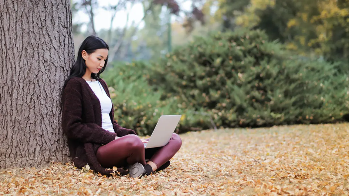 Digital guides - online security and privacy A young woman using a computer laptop under a tree