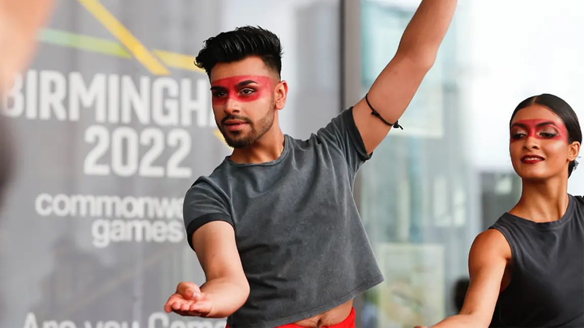 £6million for Birmingham 2022 Commonwealth Games Cultural Festival Two people striking a dance pose in front of a 'Commonwealth Games' sign