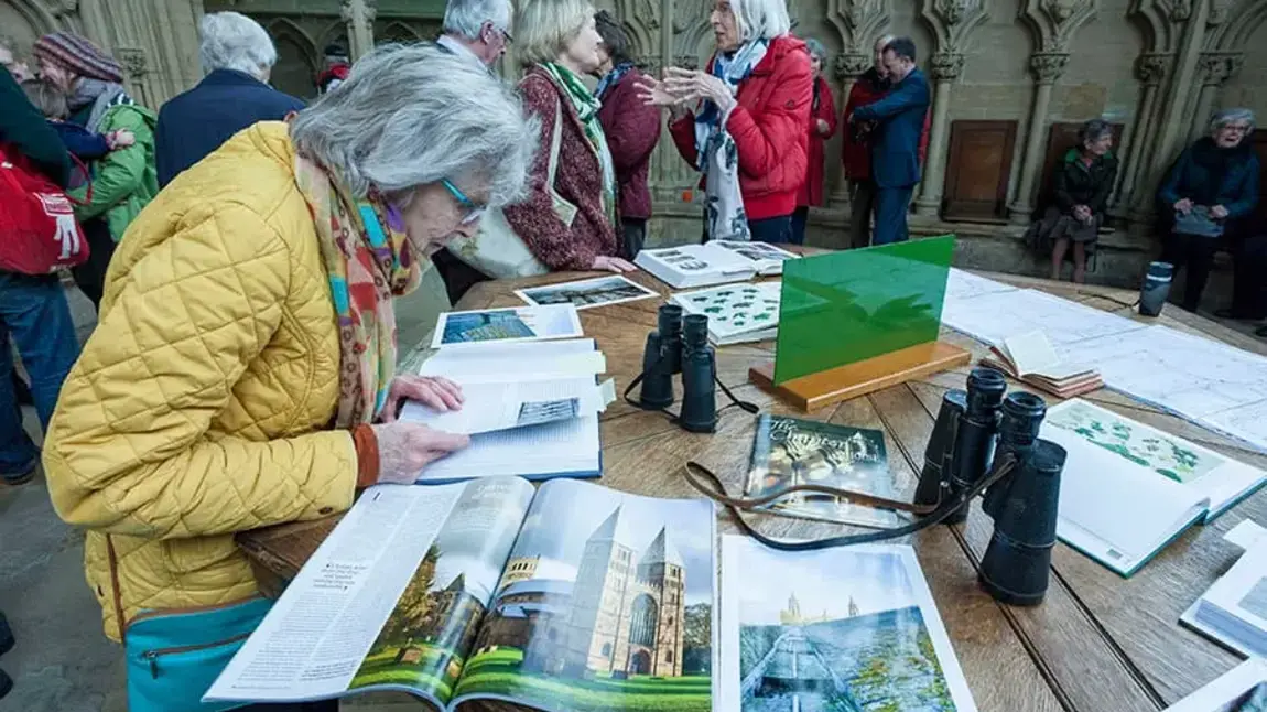 An older woman looks at magazines and leaflets on a table in a busy church