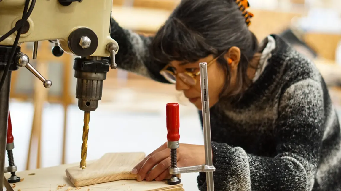 A woman drilling a hole in wood with a power tool
