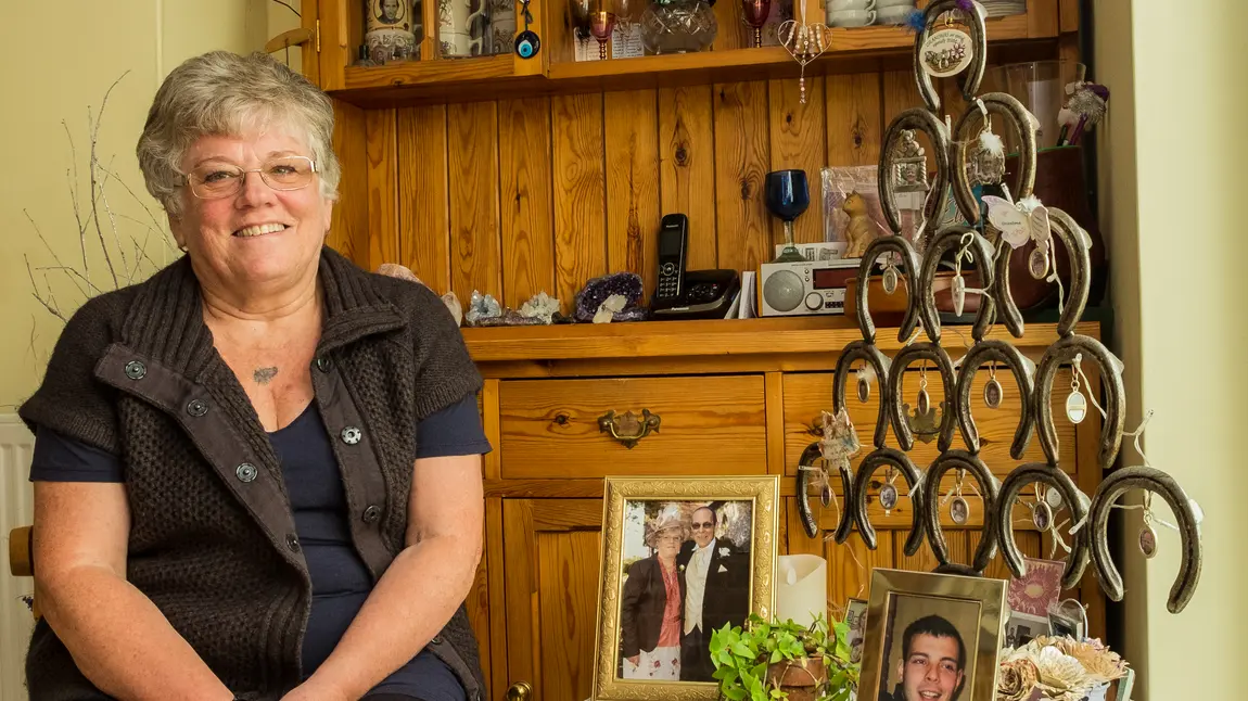 Changing lives: how art helped Angela through bereavement Angela sits in her home, with photos of her late husband and grandson