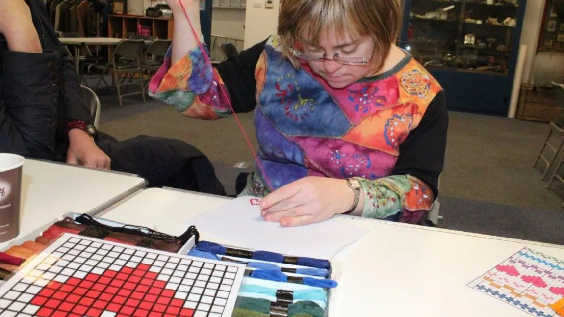 All-inclusive heritage adventures Sara, Mencap oral historian, trying cross stitching