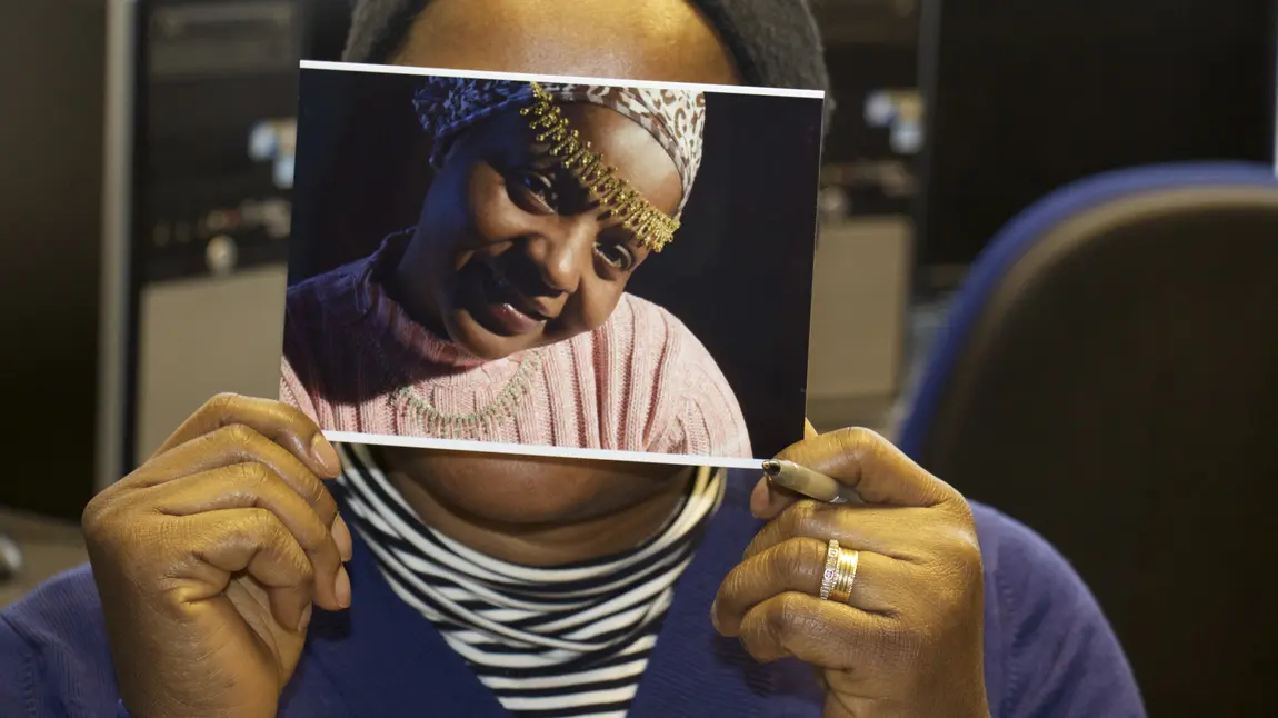 Changing Lives: Empowering women, creating a sisterhood A woman holds a photograph over her face