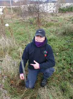 A young man next to a tree he has planted